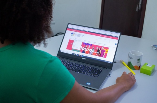 A foto mostra uma moça de blusa verde, de costas, navegando no site da UEMASUL em um notebook.