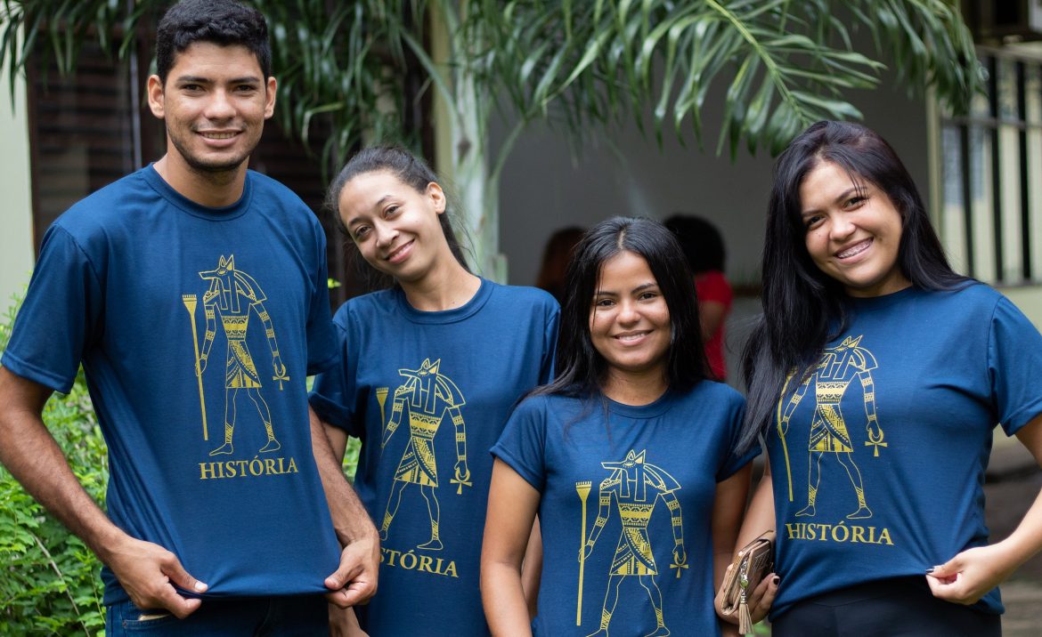 Acadêmicos do curso de História exibem posam para foto com as camisetas do curso.