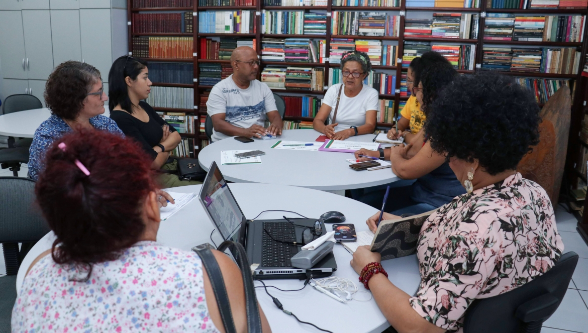 Oito professores, sentados à mesa, discutem sobre o projeto Caminhos do Sertão.