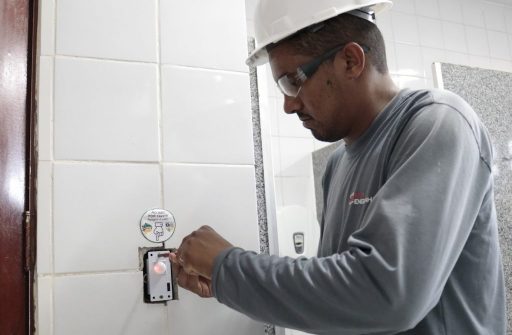 Eletricista instala sensor de movimento em banheiro.